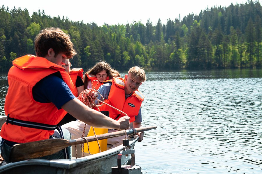 Elever i roddbåt tar prover i sjön.