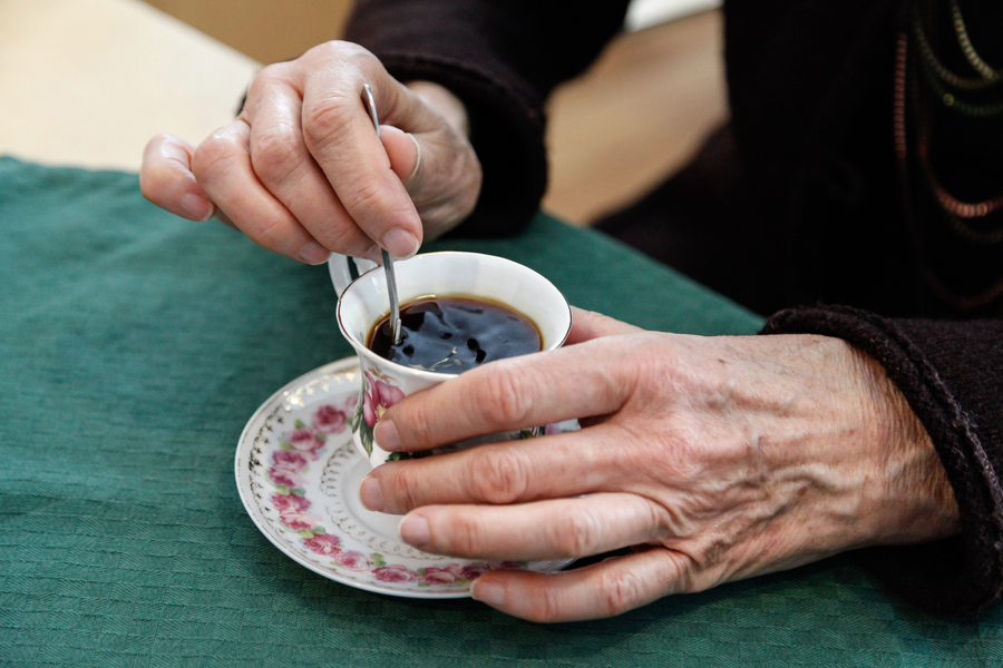 En närbild på ett par händer som håller i en kaffekopp.