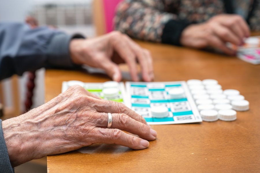 Närbild på ett par äldre händer som spelar bingo.